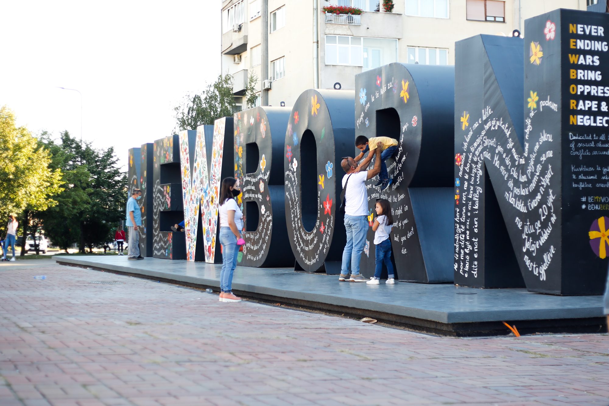 Photo of people in front of a large scale art piece that states Newborn